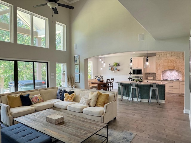 201 Deen Dr, Houston, TX 77336 - living area featuring a towering ceiling, a ceiling fan, light wood-style flooring, and arched walkways