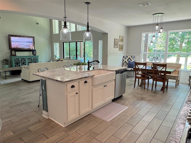 201 Deen Dr, Houston, TX 77336 - kitchen featuring a sink, white cabinetry, wood tiled floors, light stone countertops, and hanging light fixtures
