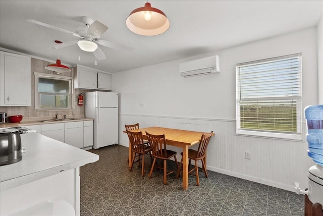 227 Detenbeck Ave, Surfside Beach, TX 77541 - dining area featuring an AC wall unit, wainscoting, dark flooring, baseboards, and ceiling fan
