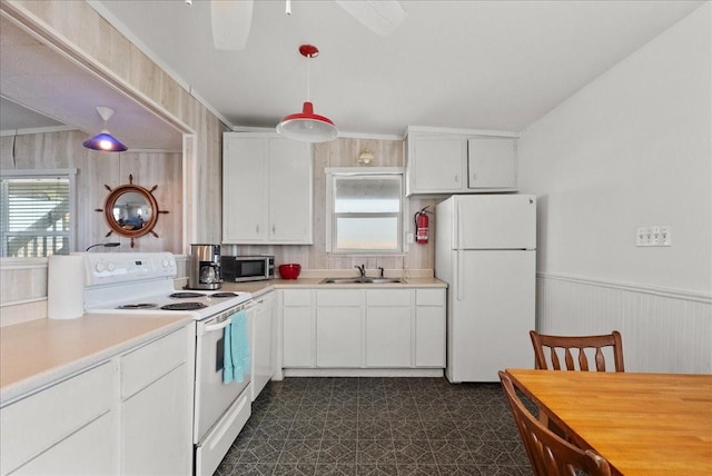 227 Detenbeck Ave, Surfside Beach, TX 77541 - kitchen featuring white appliances, a sink, dark flooring, healthy amount of natural light, and a wainscoted wall