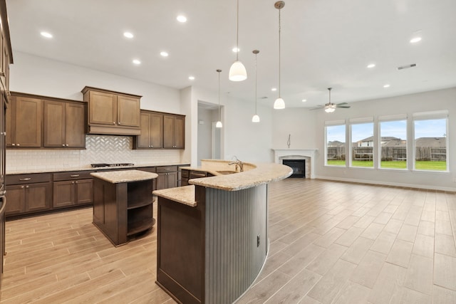 5204 Andorra Bend Ln, Porter, TX 77365 - kitchen featuring a kitchen island, gas cooktop, tasteful backsplash, a sink, and light stone countertops