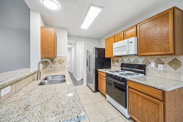 10410 Caribou Cv, Missouri City, TX 77459 - kitchen with range with gas stovetop, white microwave, a sink, stainless steel fridge with ice dispenser, and backsplash