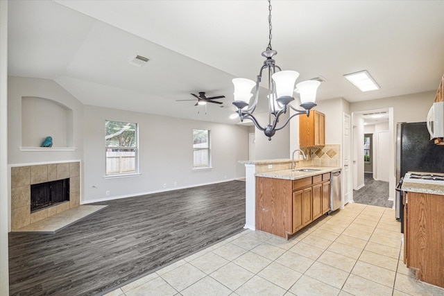 10410 Caribou Cv, Missouri City, TX 77459 - kitchen with stainless steel dishwasher, a sink, a chandelier, light tile patterned floors, and brown cabinets