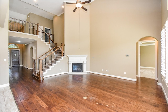 17218 Meek Pass Dr, Cypress, TX 77433 - unfurnished living room with a high ceiling, arched walkways, a ceiling fan, stairway, and hardwood / wood-style floors