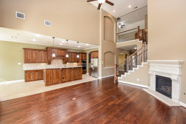 17218 Meek Pass Dr, Cypress, TX 77433 - unfurnished living room with a ceiling fan, a towering ceiling, light wood finished floors, a glass covered fireplace, and baseboards