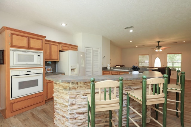 23302 Green Forest St, Hockley, TX 77447 - kitchen featuring white appliances, light wood-type flooring, a ceiling fan, open floor plan, and brown cabinets