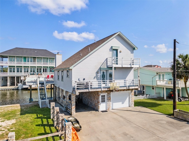 16703 Managua Way, Jamaica Beach, TX 77554 - view of front of home featuring an attached garage, concrete driveway, stone siding, a balcony, and a front yard