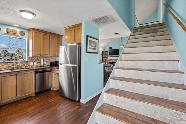 16703 Managua Way, Jamaica Beach, TX 77554 - kitchen with appliances with stainless steel finishes, a sink, dark wood-style flooring, backsplash, and brown cabinetry