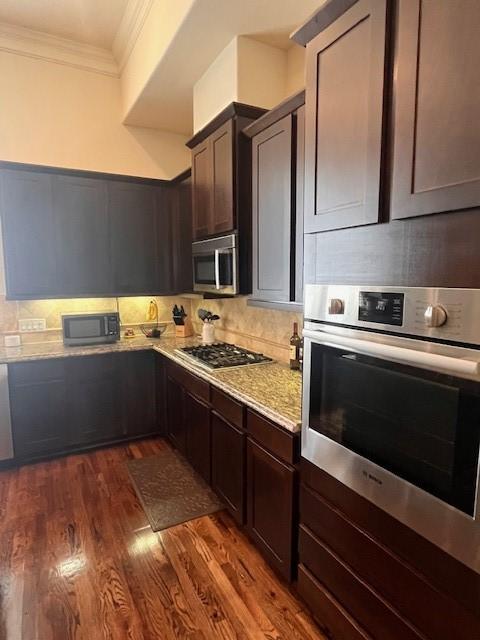 2533 Lamar St, Houston, TX 77003 - kitchen featuring appliances with stainless steel finishes, ornamental molding, dark wood-type flooring, tasteful backsplash, and dark brown cabinetry