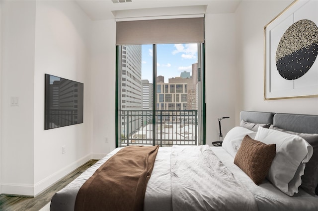 1211 Caroline St Unit 906, Houston, TX 77002 - bedroom with access to exterior, wood finished floors, baseboards, and a city view