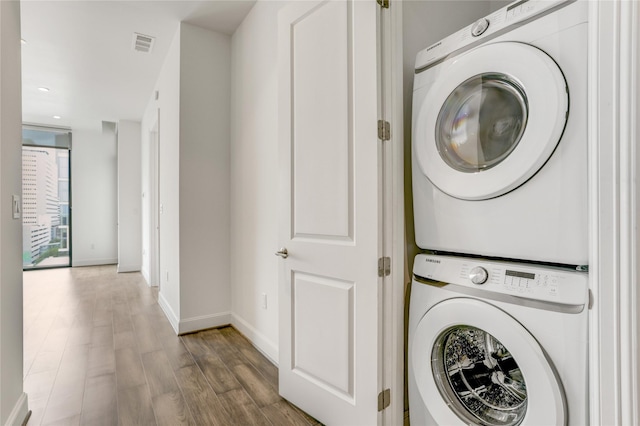 1211 Caroline St Unit 906, Houston, TX 77002 - laundry area with estacked washer and dryer, wood finished floors, baseboards, and recessed lighting