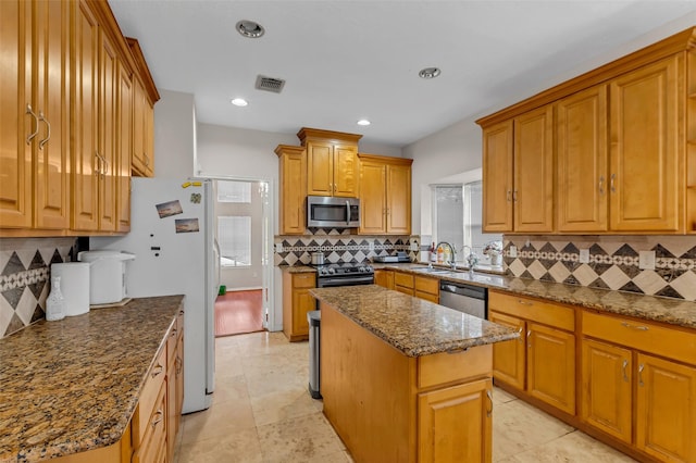 3714 Green Fields Dr, Sugar Land, TX 77479 - kitchen with stainless steel appliances, tasteful backsplash, a kitchen island, dark stone countertops, and brown cabinetry