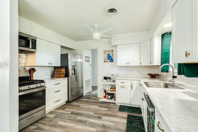 117 Tuna St, Galveston, TX 77550 - kitchen featuring appliances with stainless steel finishes, tasteful backsplash, and white cabinetry