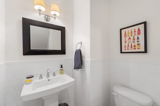 1807 Ashland St, Houston, TX 77008 - bathroom featuring tile walls, toilet, a wainscoted wall, and a sink
