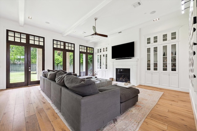 5420 Maple St, Bellaire, TX 77401 - living area with a ceiling fan, french doors, beamed ceiling, light wood-style flooring, and a glass covered fireplace