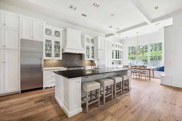 5420 Maple St, Bellaire, TX 77401 - kitchen featuring built in refrigerator, custom range hood, white cabinetry, light wood finished floors, and a breakfast bar area