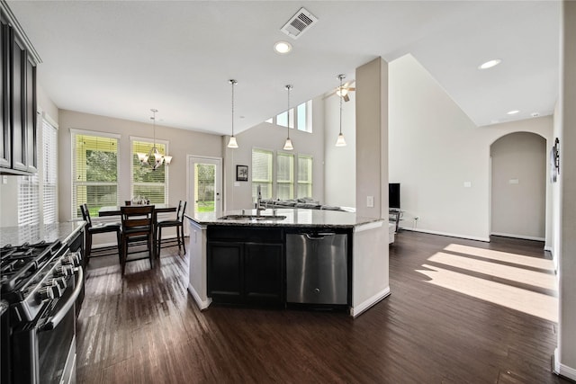 2635 Cedar Path Ln, Conroe, TX 77385 - kitchen featuring appliances with stainless steel finishes, a sink, dark wood finished floors, arched walkways, and light stone countertops