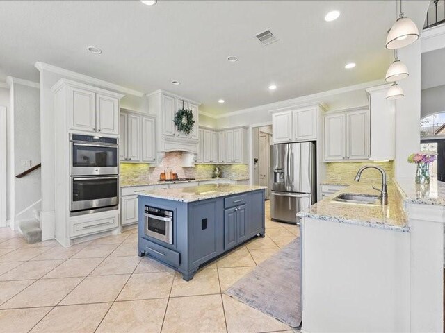 20326 Scarlett Saddle Ct, Cypress, TX 77433 - kitchen with appliances with stainless steel finishes, a sink, ornamental molding, blue cabinets, and light tile patterned flooring