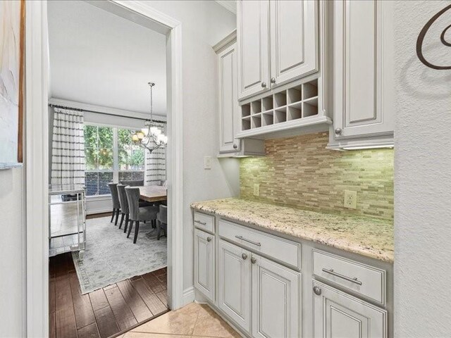 20326 Scarlett Saddle Ct, Cypress, TX 77433 - kitchen featuring backsplash, a chandelier, light stone counters, and wood finished floors