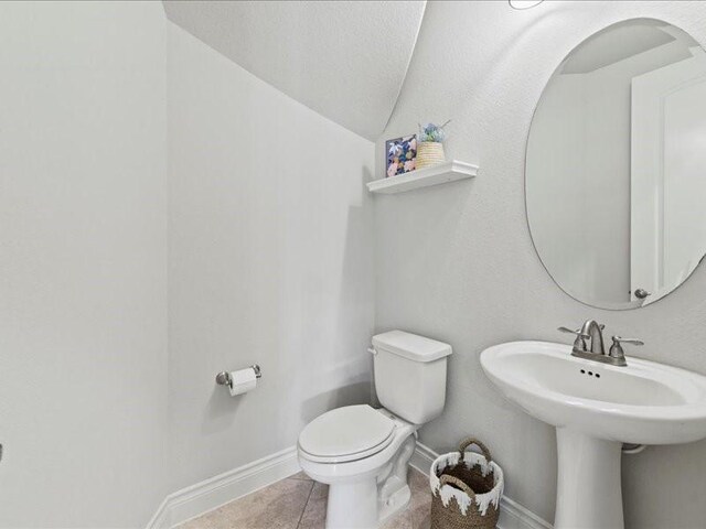 20326 Scarlett Saddle Ct, Cypress, TX 77433 - half bathroom featuring toilet, vaulted ceiling, baseboards, and tile patterned flooring