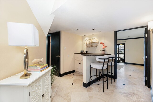 18138 Bal Harbour Dr, Houston, TX 77058 - kitchen featuring a breakfast bar area, white cabinets, baseboards, and dark countertops