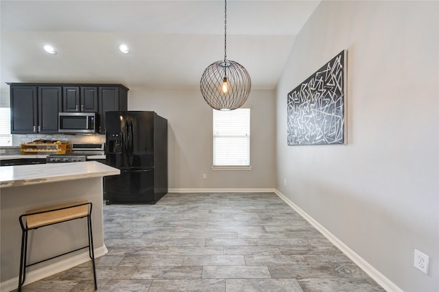 21811 Blossom Grove Ln, Spring, TX 77379 - kitchen featuring black refrigerator with ice dispenser, stainless steel microwave, range, backsplash, and hanging light fixtures