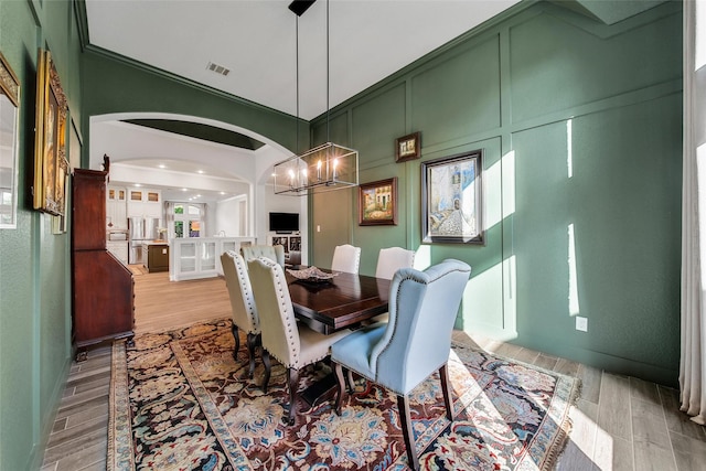 7118 Kinglet Ct, Katy, TX 77493 - dining area featuring light wood finished floors, a chandelier, arched walkways, and a high ceiling