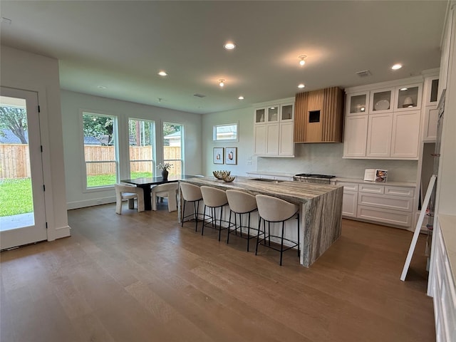 1846 Hewitt Dr, Houston, TX 77018 - kitchen featuring white cabinets, recessed lighting, wood finished floors, a center island, and a breakfast bar area