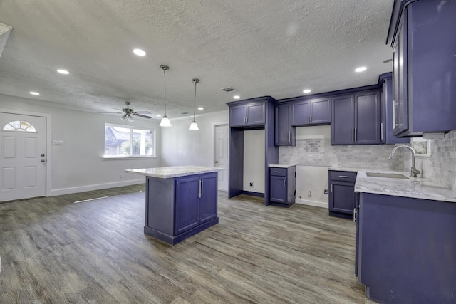 7437 Navasota St, Houston, TX 77016 - kitchen with a sink, ceiling fan, a kitchen island, a textured ceiling, and wood finished floors