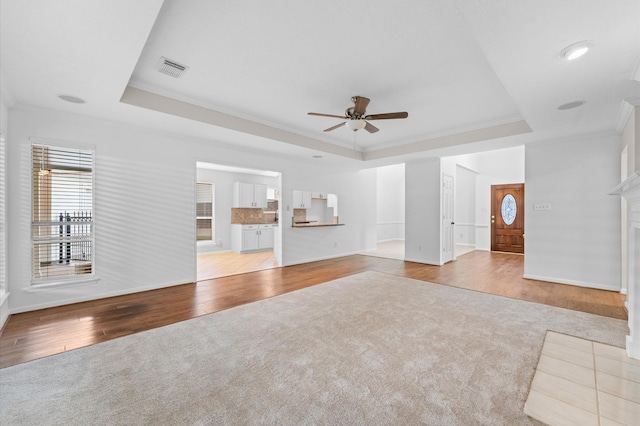 6119 Plantation Bay Dr, Katy, TX 77449 - unfurnished living room featuring a tray ceiling, ceiling fan, light carpet, ornamental molding, and baseboards