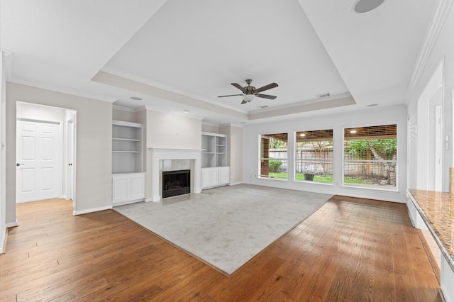 6119 Plantation Bay Dr, Katy, TX 77449 - unfurnished living room with a raised ceiling, light wood-style flooring, a ceiling fan, crown molding, and a tile fireplace