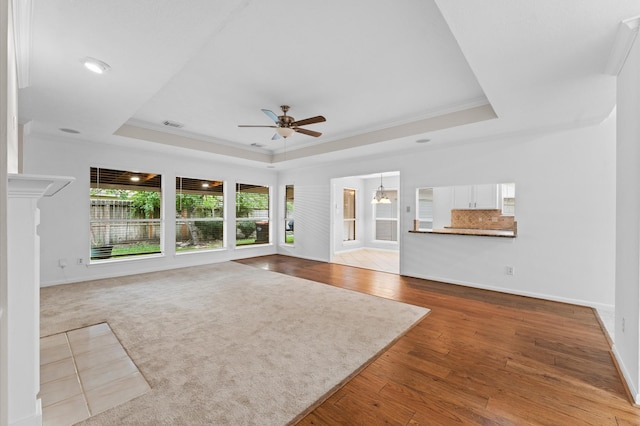 6119 Plantation Bay Dr, Katy, TX 77449 - unfurnished living room featuring a raised ceiling, a ceiling fan, ornamental molding, baseboards, and wood finished floors