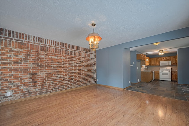 144 Pin Oak Ln, Hempstead, TX 77445 - unfurnished living room featuring a sink, dark wood-type flooring, brick wall, baseboards, and a textured ceiling
