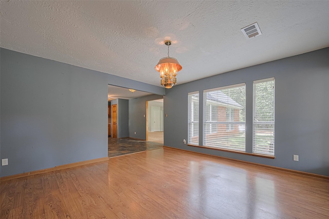 144 Pin Oak Ln, Hempstead, TX 77445 - empty room featuring wood finished floors, a chandelier, baseboards, and a textured ceiling