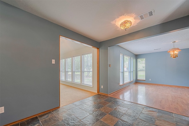 144 Pin Oak Ln, Hempstead, TX 77445 - spare room featuring baseboards, stone tile flooring, and a chandelier