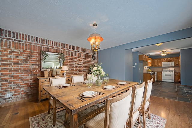 144 Pin Oak Ln, Hempstead, TX 77445 - dining area with brick wall, dark wood-style floors, ceiling fan, and a chandelier