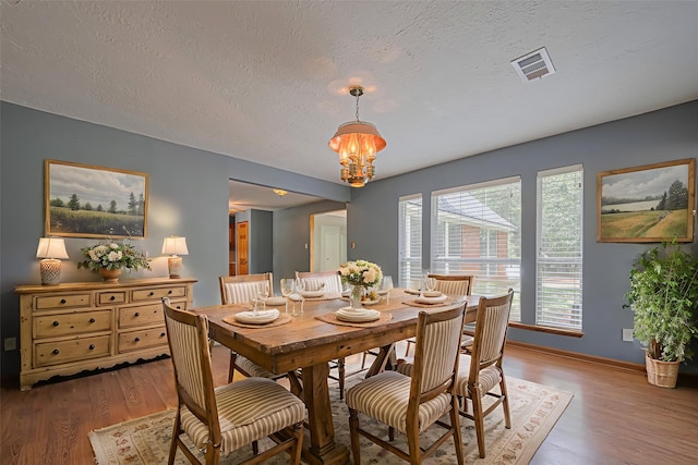 144 Pin Oak Ln, Hempstead, TX 77445 - dining space with wood finished floors, a chandelier, a textured ceiling, and baseboards