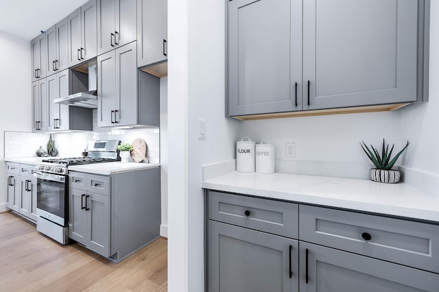 3808 Jefferson St, Houston, TX 77003 - kitchen with stainless steel range with gas stovetop, wall chimney exhaust hood, gray cabinetry, and light wood-type flooring