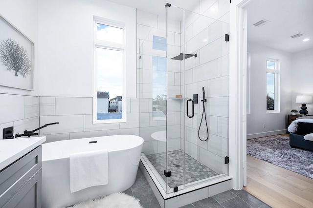 3808 Jefferson St, Houston, TX 77003 - bathroom with a soaking tub, tile walls, a stall shower, ensuite bathroom, and wood finished floors