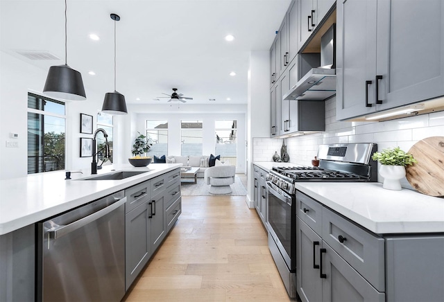 3808 Jefferson St, Houston, TX 77003 - kitchen featuring stainless steel appliances, a sink, wall chimney range hood, gray cabinetry, and a ceiling fan