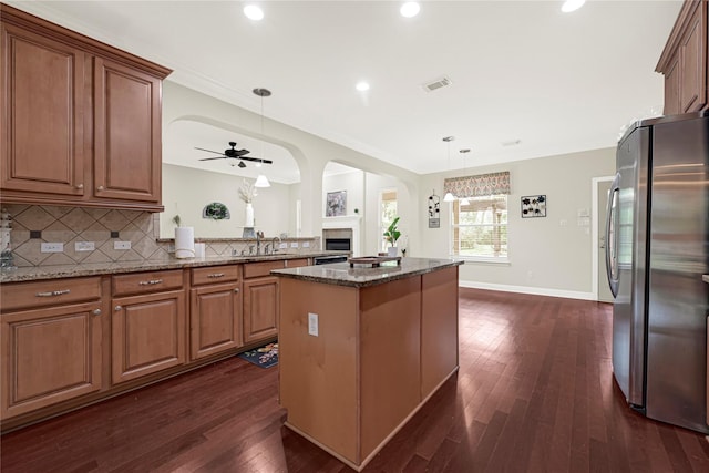 3730 Arundel Gardens Ln, Sugar Land, TX 77498 - kitchen featuring freestanding refrigerator, a center island, dark stone counters, ceiling fan, and dark wood-type flooring