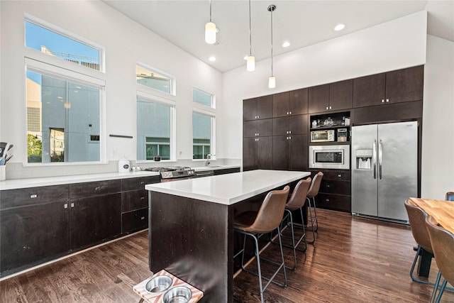 104 Pierce St, Houston, TX 77002 - kitchen with stainless steel appliances, dark wood-style floors, dark brown cabinetry, a sink, and a kitchen island