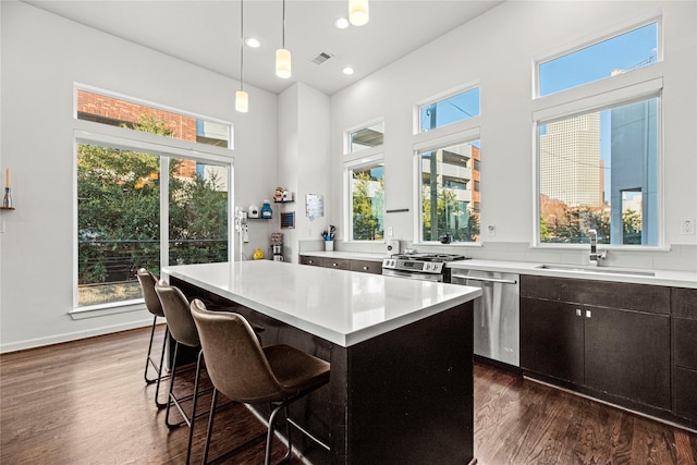 104 Pierce St, Houston, TX 77002 - kitchen with stainless steel appliances, a sink, dark wood-style flooring, light countertops, and a breakfast bar
