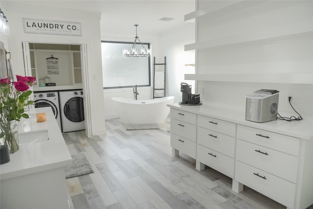 323 E Palm St, Fresno, TX 77545 - bathroom with independent washer and dryer, a freestanding tub, a chandelier, double vanity, and wood finished floors