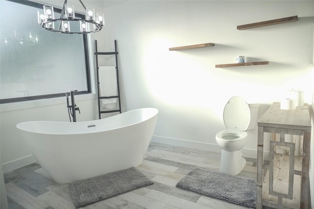 323 E Palm St, Fresno, TX 77545 - bathroom featuring a chandelier, a soaking tub, and wood finished floors