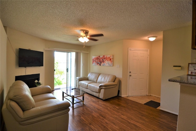2121 Hepburn Sts Unit 713, Houston, TX 77054 - living room featuring a ceiling fan, wood finished floors, a fireplace, a textured ceiling, and baseboards