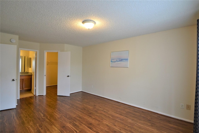 2121 Hepburn Sts Unit 713, Houston, TX 77054 - unfurnished bedroom with dark wood-style flooring, a walk in closet, a textured ceiling, and baseboards