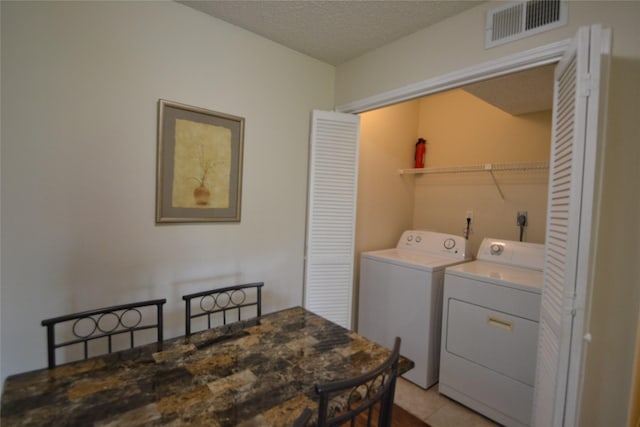 2121 Hepburn Sts Unit 713, Houston, TX 77054 - laundry room featuring washer and dryer, a textured ceiling, and light tile patterned flooring