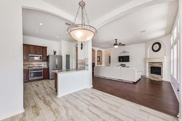 7518 Rain Meadow Ln, Cypress, TX 77433 - kitchen with stainless steel appliances, arched walkways, open floor plan, backsplash, and ceiling fan