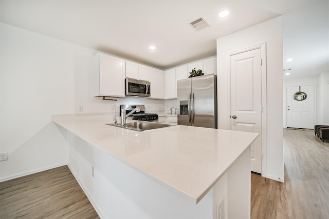 337 Riverwood Village Ln, Sealy, TX 77474 - kitchen with stainless steel appliances, light wood-type flooring, light countertops, a peninsula, and white cabinets